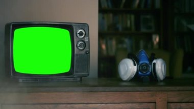 El, Yeşil Ekranlı bir yüz maskesi ve Retro TV alıyor. Duman Arkaplanı. Yeşil Ekranı İstediğiniz Görüntü ile Değiştirebilir veya Sonraki Efektlerde Anahtarlama Efekti ile Değiştirebilirsiniz. 
