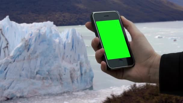 在冰川附近使用老式智能手机绿色屏幕的男性手 你可以用你想要的镜头或图片代替绿色屏幕 你可以用关键的效果来做 — 图库视频影像