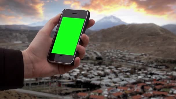 男性の手は アルゼンチンのアンデス地方の山村の近くで古いスマートフォンを保持しています 緑の画面を必要な映像や画像に置き換えることができます キー効果でそれを行うことができます — ストック動画