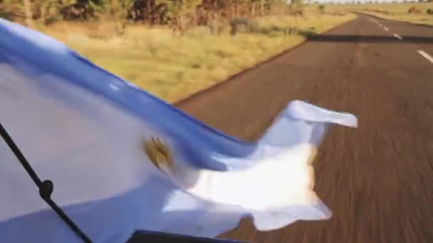 道路上の車の後ろからぶら下がっているアルゼンチン国旗 — ストック動画