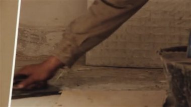 İnşaat işçisi yeni bir evin zemininde çalışıyor. Yakın plan. 