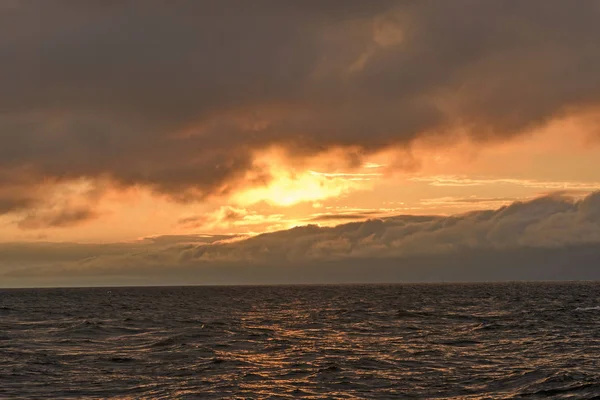 Soleil scrutant les nuages au-dessus des vagues — Photo