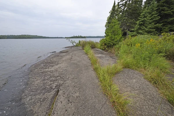 Oude stenen op de oever van het meer van een wildernis — Stockfoto