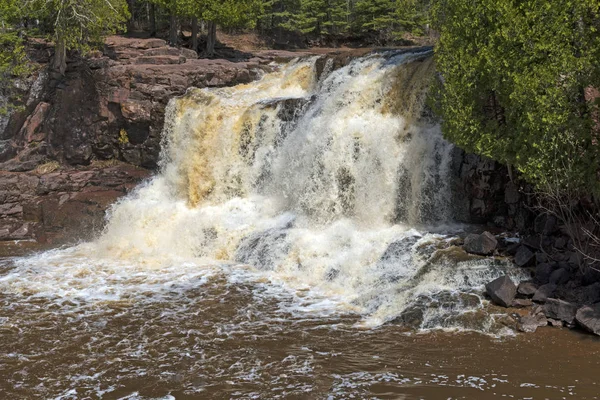 Vårvatten på ett vattenfall mitt bland röda klippor — Stockfoto