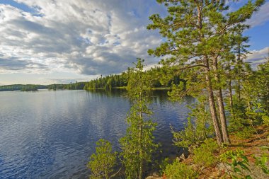Ontario 'daki Quetico İl Parkı' ndaki Saganagons Gölü 'ndeki Kuzey Ormanı' nda Güneş ve Bulutlar