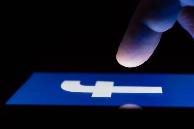 Moskova, Rusya - 9 Mayıs 2018: Facebook logo görüntüleme karanlıkta bir masada yalan bir smartphone. Parmak dokunmatik ekran üzerinde. Popüler sosyal ağlarda bağımlılık kavramı.