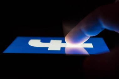 Moskova, Rusya - 9 Mayıs 2018: Facebook logo görüntüleme karanlıkta bir masada yalan bir smartphone. Parmak dokunmatik ekran üzerinde. Popüler sosyal ağlarda bağımlılık kavramı.