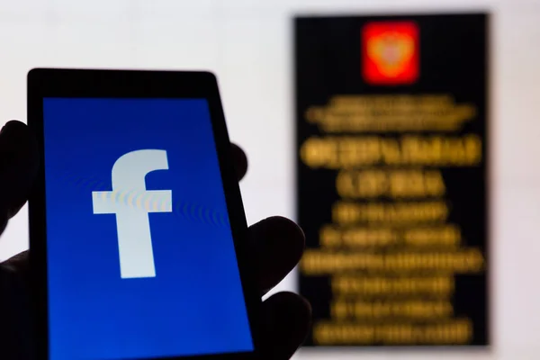 МОСКВА, РОССИЯ - 9 мая 2018 года: Смартфон в руке с логотипом популярной социальной сети Facebook. Вход в офис Роскомнадзора (РКН). Общая концепция защиты данных (GDPR). Цензура — стоковое фото