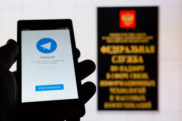 MOSCA, RUSSIA - 9 MAGGIO 2018: Smartphone in mano con popolare app di messaggistica sicura Telegram sullo sfondo di un cartello all'ingresso dell'edificio Roskomnadzor (RKN) . — Foto Stock