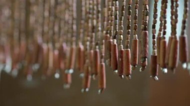 Tahta perdeler kapının önünde dalgalanıyor. Bambu boncuklar sallanıyor.