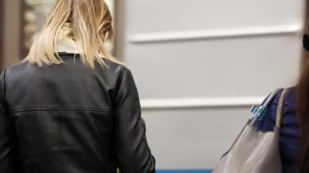 俄罗斯莫斯科 2019年10月26日 身穿黑色皮夹克的年轻金发女子在智能手机上 在一辆地铁列车的背景下写下信息 列车月台上的乘客发短信 — 图库视频影像