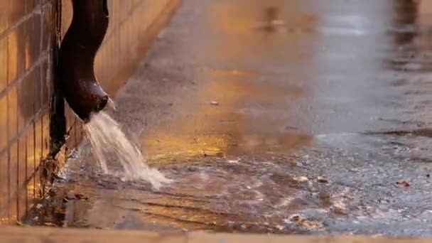 Het water stroomt uit een afvoerpijp de straat op. Een krachtige stroom stroomt — Stockvideo