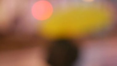 Arka plan bulanık. Sarı şemsiyeli, tanınmayan bir adam sokakta yürüyor.