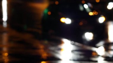 Geceleri ıslak asfalt arka planında bulanık insan siluetleri