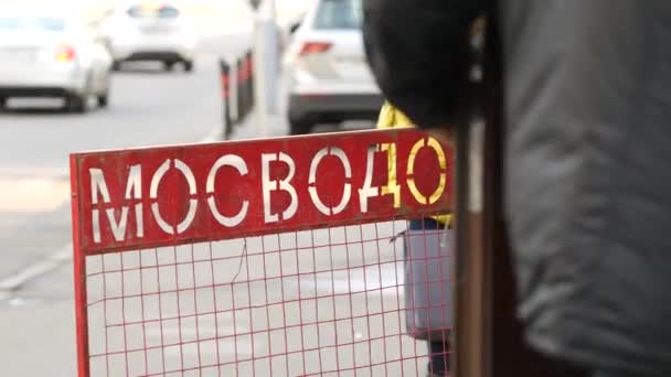 Fence made of red steel mesh with inscription MOSVODOSTOK on sidewalk near house — Stock Video