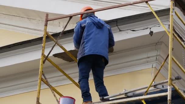 Trabalhador de construção em uma decoração de bandaid de andaime em um edifício. Durante o dia . — Vídeo de Stock