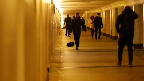 As pessoas caminham ao longo da passadeira subterrânea no final da noite. Lanterna laranja — Vídeo de Stock