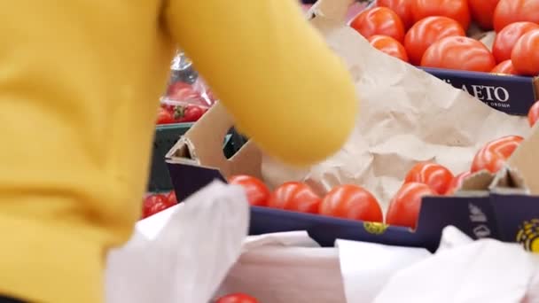 Winkelaars in de supermarkt kiezen verse tomaten. Golfkartonnen doos — Stockvideo