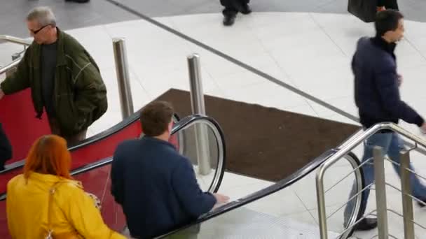 Os visitantes do shopping center descem e escalam a escada rolante . — Vídeo de Stock