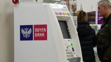 Moskova, Rusya - 26 Ekim 2019: Posta Bankası logosunun kırmızı ve mavi olduğu beyaz bankamatik. Rus Post 'un binasında bir adam var..