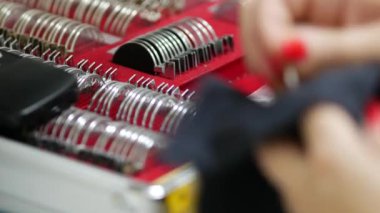 Göz doktoru optik lensleri optalmolog muayenehanesinde test etmek için peçeteyle siliyor. İçinde lensler ve aksesuarlar olan bavul.