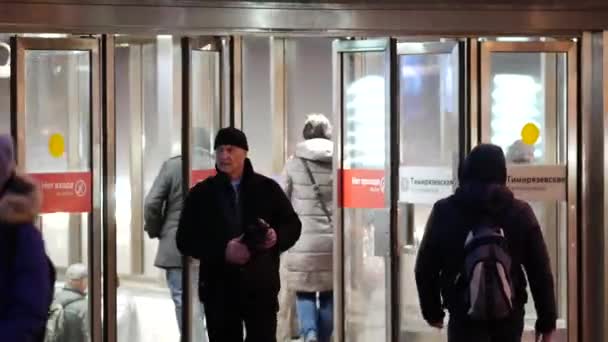 Moscow, Russia - November 26, 2019: People exit the glass doors of the entrance to the metro Timiryazevskaya. Glass walls of a lighted structure. Passengers depart from the subway in the evening — Stock Video