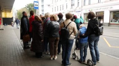 Bir grup turist kaldırımda durur ve rehberi dinler.