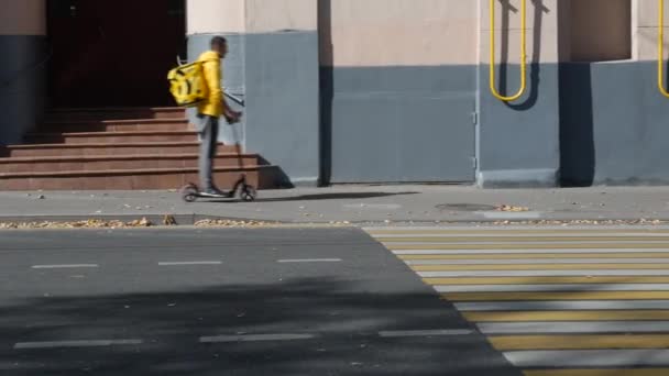 Yandex Eda koerier rent op elektrische scooter op de stoep in het centrum van Moskou. — Stockvideo