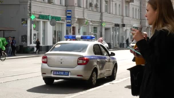 Dívka pije kávu z papírového kelímku na ulici. Policejní auto na silnici — Stock video