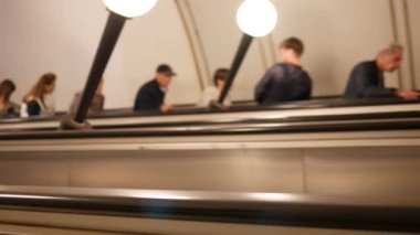 Yürüyen merdivende tanımlanamayan metro yolcuları. Bulanık yüzlü insanlar yükselir.
