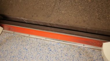 The camera is directed down to the floor of the subway car and the platform.