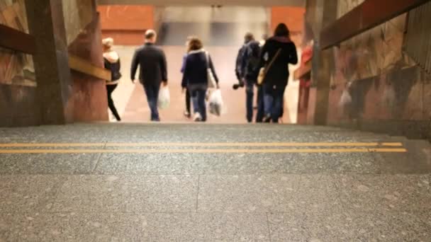 Onherkenbare metropassagiers dalen de trap af in de metrotunnel — Stockvideo