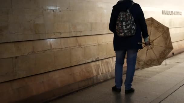 Неузнаваемая женщина стоит на платформе метро с открытым зонтиком и спинами — стоковое видео