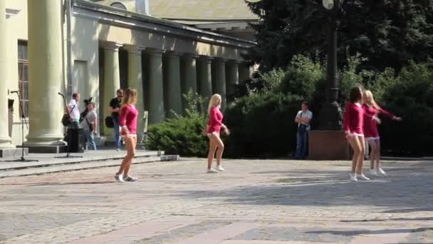 Flickor från cheerleading laget i rosa tunikor dansar på lekplatsen — Stockvideo