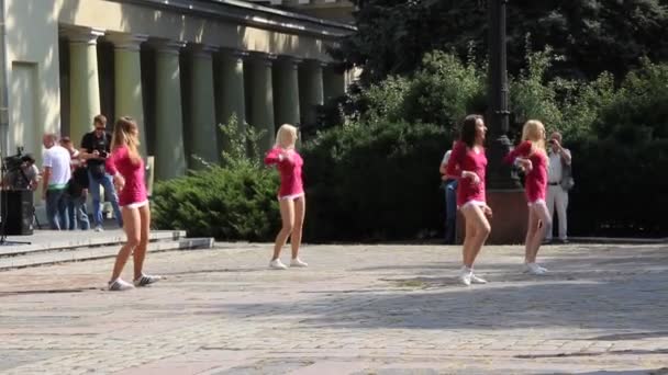 Flickor från cheerleading laget i rosa tunikor dansar på lekplatsen. — Stockvideo