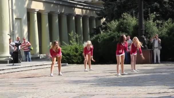 Les filles de l'équipe de pom-pom girls en tuniques roses dansent sur l'aire de jeux . — Video