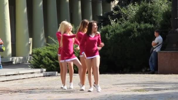 Дівчата з команди черлідером у рожевих туніках танцюють на ігровому майданчику.. — стокове відео