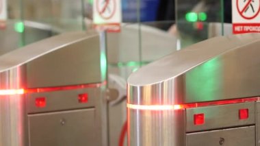 Turnike metrosu. İnsanlar kapıların arasından geçer. Renk göstergeleri yanıp sönüyor