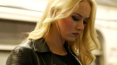 Uzun saçlı genç sarışın bir kadın bir arabanın kapısında duruyor..