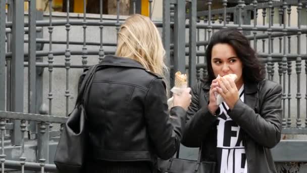 Egy barna nő őszi fekete bőrdzsekiben megeszi a shawarmát. Két barátnő. — Stock videók