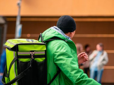 Moskova, Rusya - 19 Ekim 2019: Üniformalı Asya kökenli kurye ve sokakta bisikletli yeşil teslimat kulübü çantaları. Yiyecek dağıtan şirketlerin sembolleri ve logosu olan termal çanta.