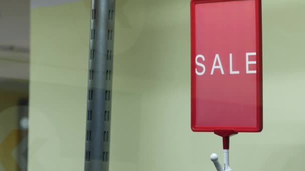 Красная табличка "ПРОДАЖА" над вешалками. Небольшой магазин организовал продажу одежды — стоковое видео