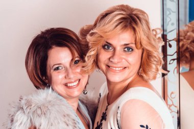 Akşam elbiseleri ve yakasında kürk yaka olan zarif kızlar. Kardeşlerim.