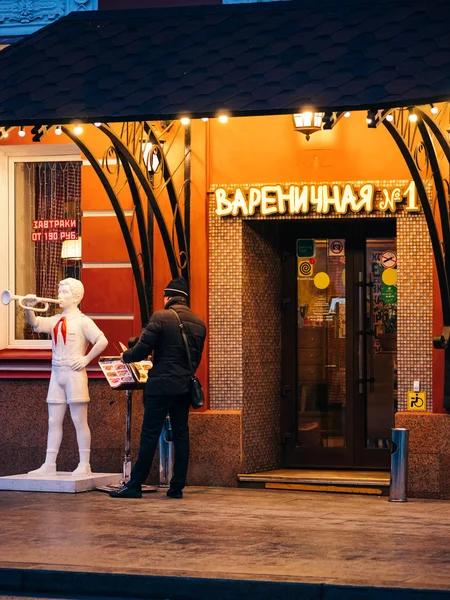 Moscow, Russia - January 17, 2020: Entrance to street cafe in city center in evening. Porch with light illumination and soviet union era sculpture of pioneer with clarion. sign text Varenichnaya No.1 — Stock Photo, Image