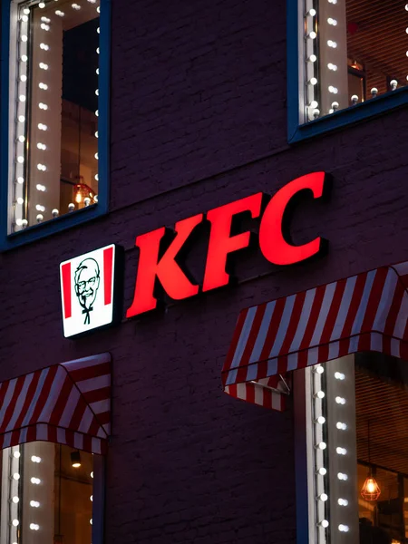 Moscow, Russia - January 17, 2020: KFC logo with red lights on wall of house in evening. Luminous windows with visors made of fabric with red stripes. Fast food restaurant near metro on Taganka — Stock Photo, Image