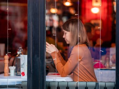 Moskova, Rusya - 17 Ocak 2020: Bir kız Verkhnyaya Radishchevskaya 'daki popüler Fransız kafe barı Jean-Jacques' ta tırnaklarını yiyor. Geleneksel Fransız mutfağı. Akşamları canlı müzik.