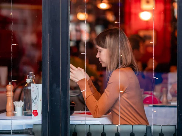 Moskova, Rusya - 17 Ocak 2020: Bir kız Verkhnyaya Radishchevskaya 'daki popüler Fransız kafe barı Jean-Jacques' ta tırnaklarını yiyor. Geleneksel Fransız mutfağı. Akşamları canlı müzik.