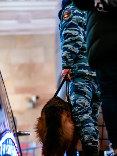 Moskva, Rusko - 17. ledna 2020: Rozmazaná figurka policisty se psem stoupá podél eskalátoru metra. Psovod v maskáčích se služebním pastýřem na vodítku. Text na záplatě je policie — Stock fotografie