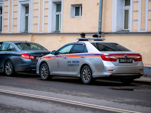 Coche de servicios especiales en calle ciudad. Conductor en uniforme sentado detrás del volante. Ministerio de Situaciones de Emergencia de Rusia. emblemas MCHS y marcas de identificación . —  Fotos de Stock