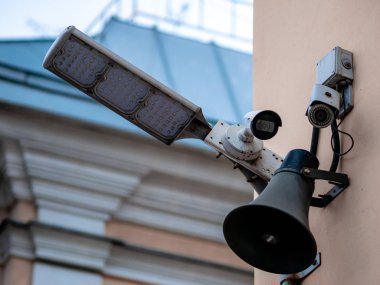 Several surveillance cameras on the wall of a house in Moscow, Russia. LED flashlight spotlight and loudspeaker on a city street. Big brother watching equipment